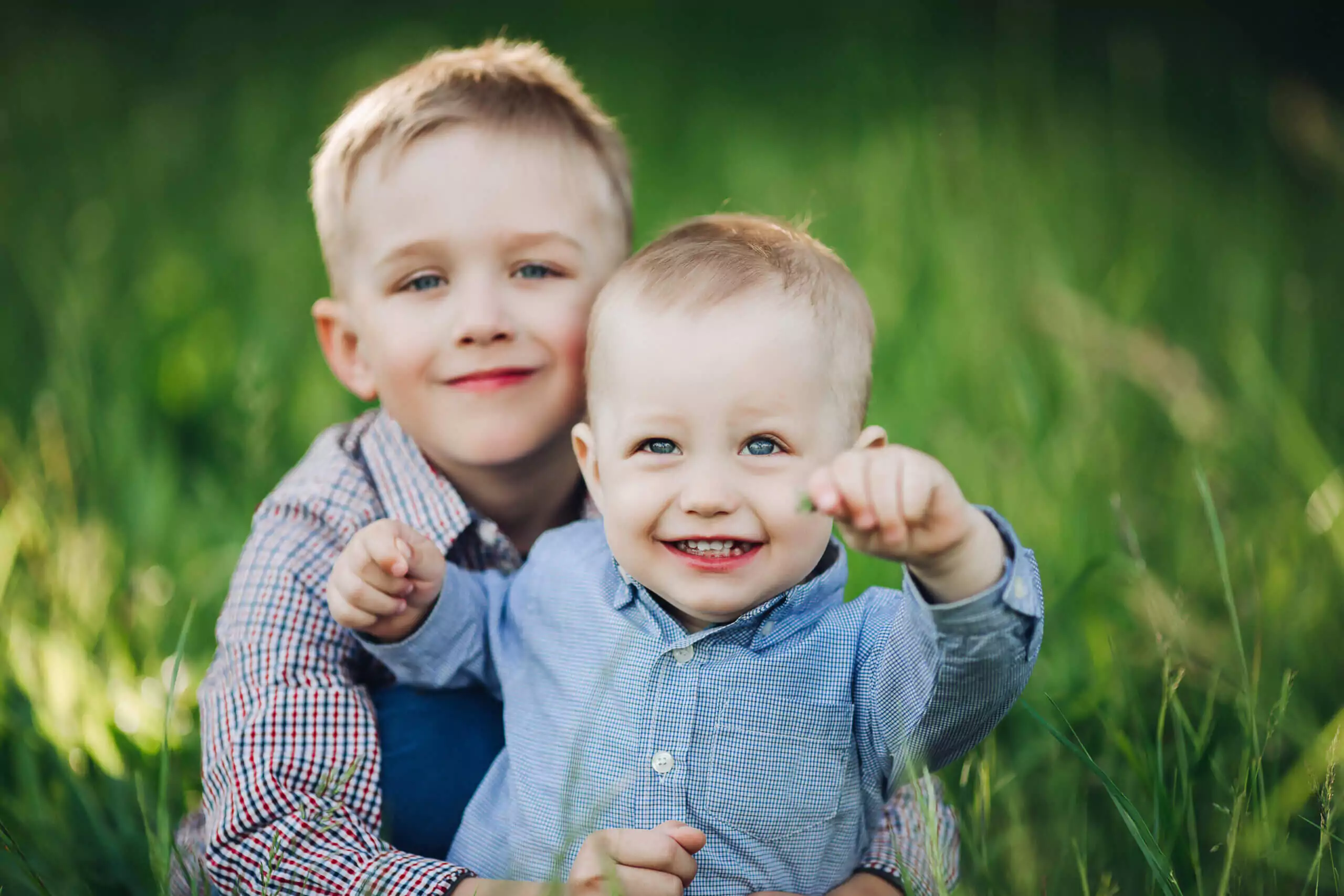 portrait-two-little-stylish-happy-brother-with-beautiful-blue-eyes-playing-park-embracing-looking-camera-boys-wearing-shirts-posing-against-green-grass-background-scaled